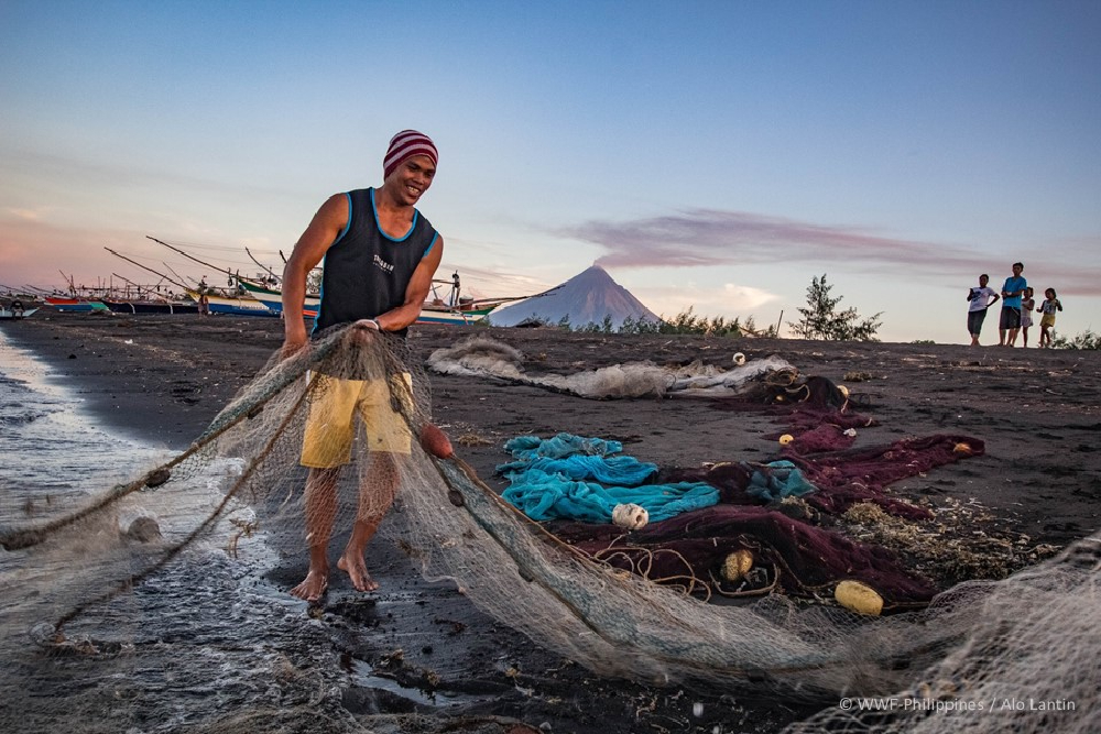 a fisherman mends his ring net down on a beach in the municipality of tiwi bicol