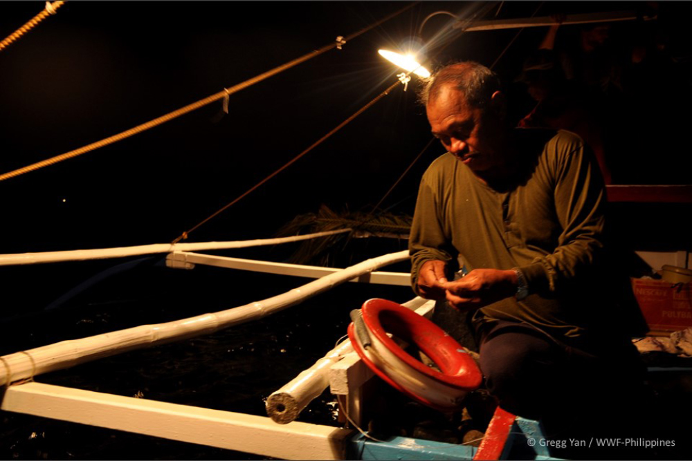 a fisherman prepares his hook for a night of handline tuna fishin