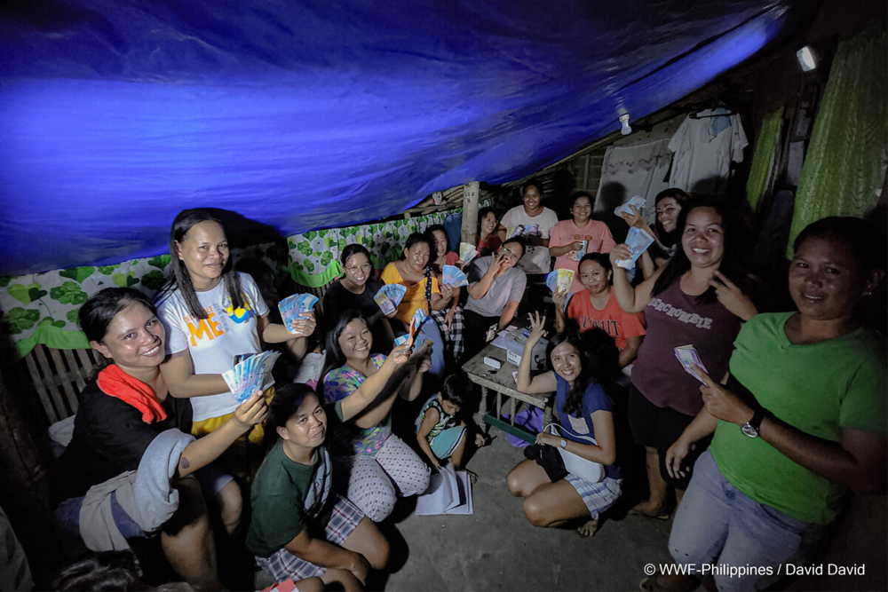 members of a gslc in occidental mindoro huddle under a tent roof as they go through their christmas cashout