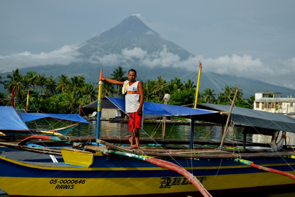 a fisherman under the shadow of mayon volcano in malbay province, luzon island