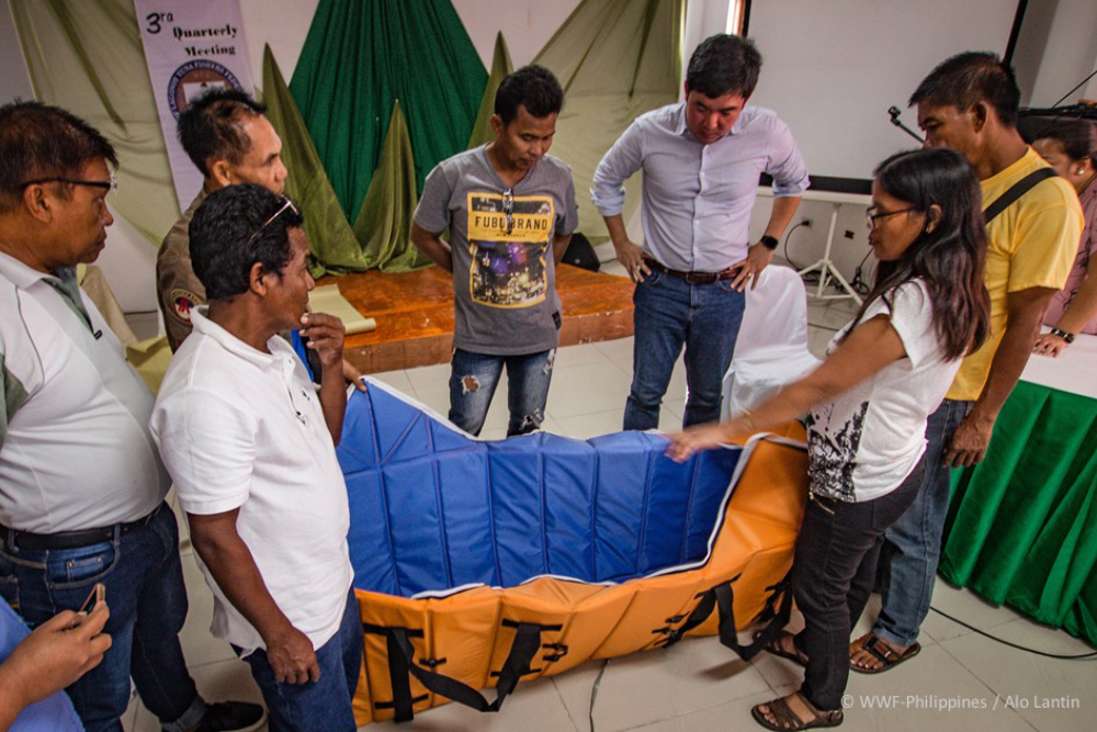 representatives from the world wide fund for nature (wwf) philippines, tambuyog development center incorporated and the gltffi stand around one of the collapsible tuna catch holds